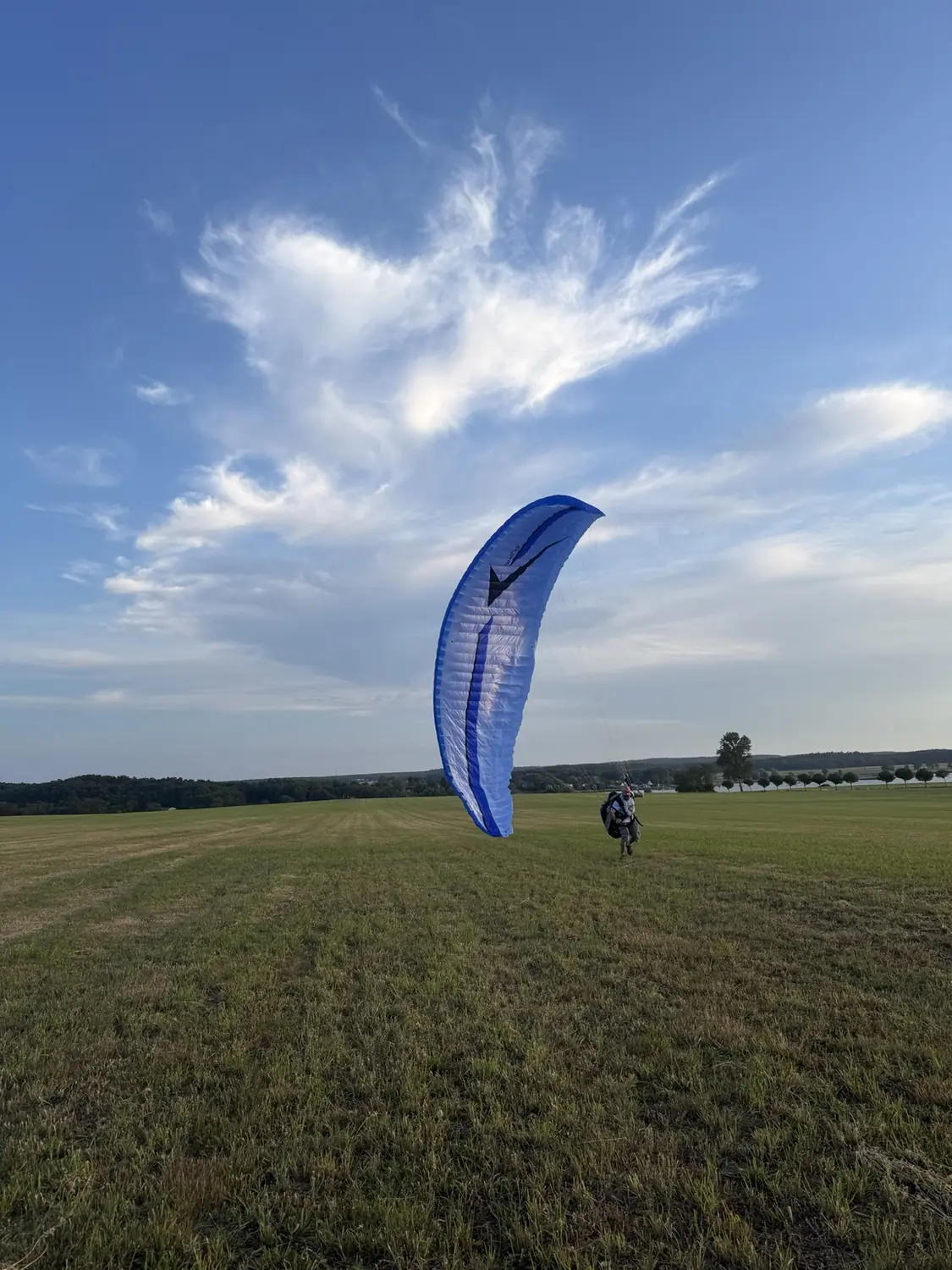 Frank mit seinem blauen Gleitschirm auf einem Feld in Brandenburg